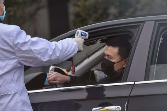 ตำรวจจีนใช้เครื่องวัดอุณหภูมิของคนขับรถที่จุดตรวจ